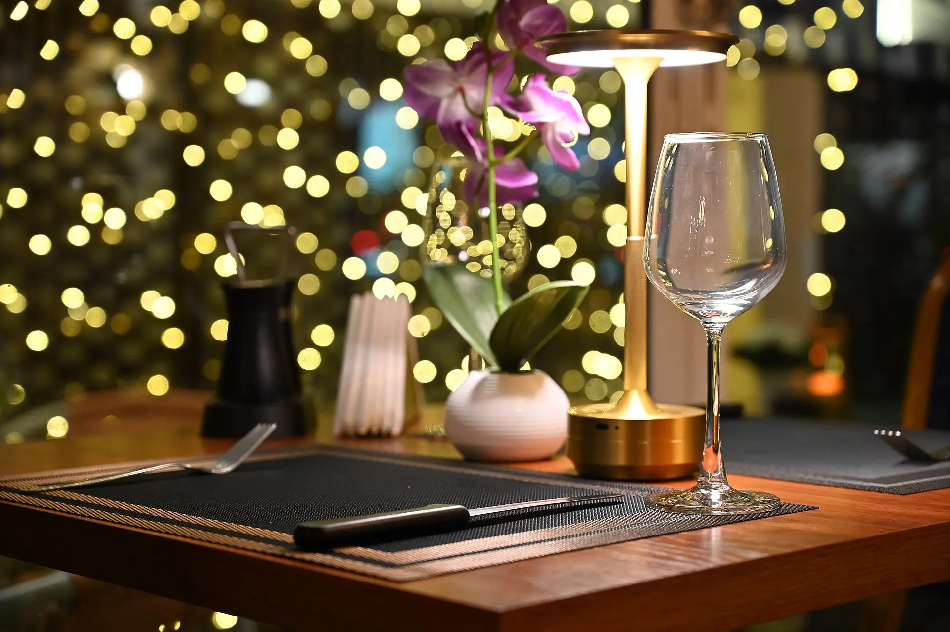 Candlelit fine-dining table with a wine glass and a golden lamp